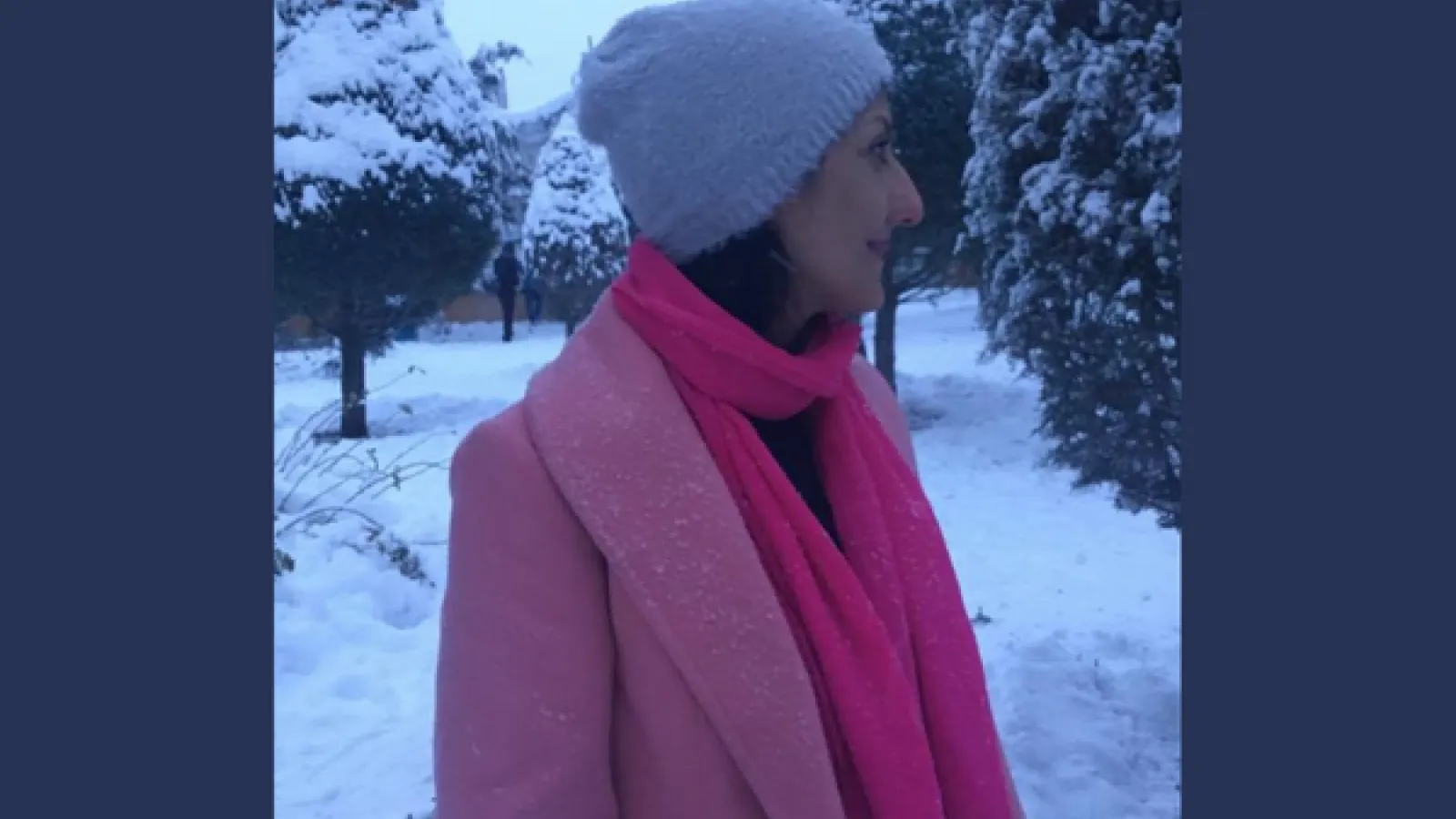 Zahra is standing in the snow with a pink coat and bright pink scarf and lavender hat