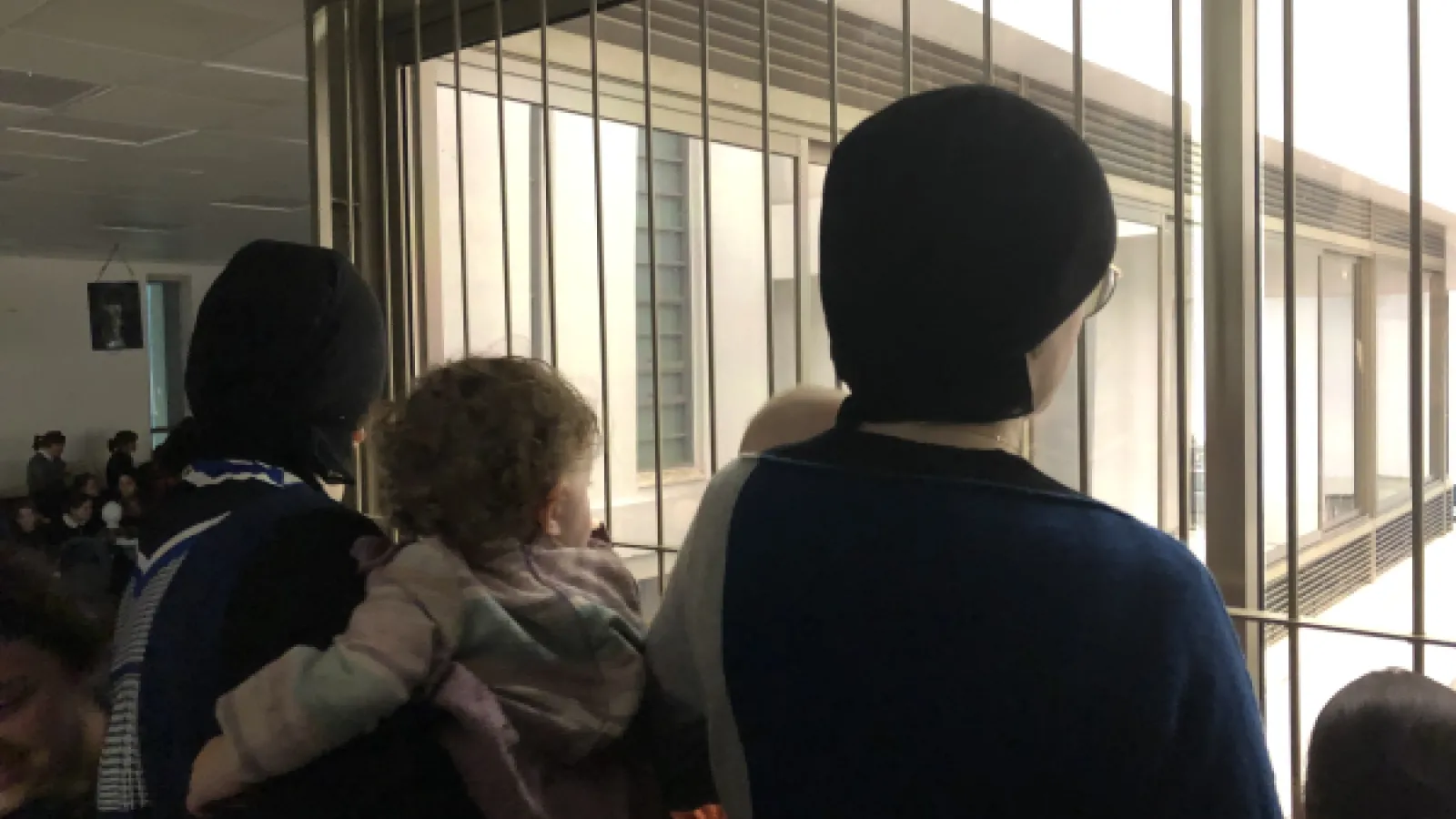 the backs of women's heads as they look out a window