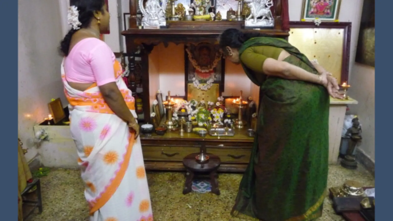 Two women stand before a street altar