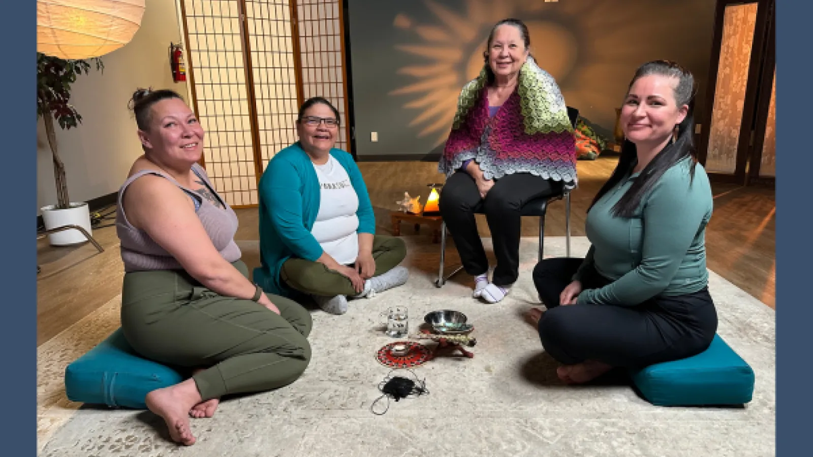 Four women sit on the floor smiling at the camera