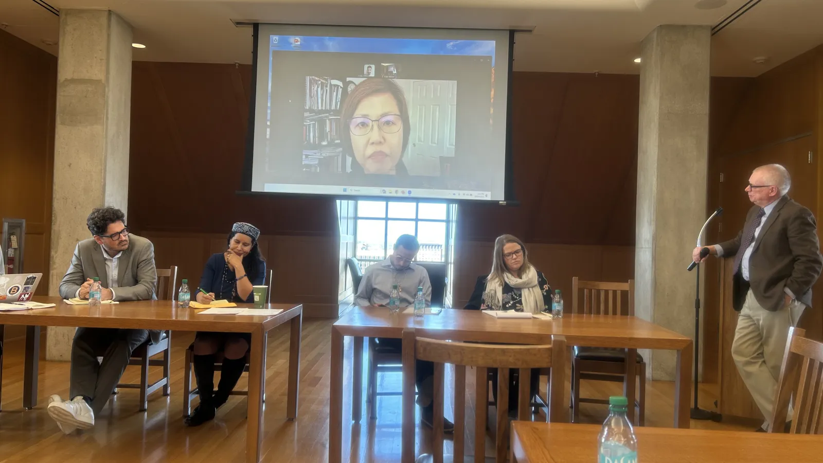 Panelists at the event sitting at a table with a screen behind them.