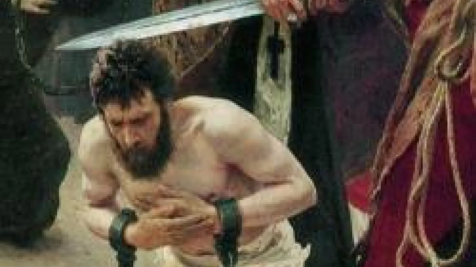 A man on his knees with his wrists bound in chains