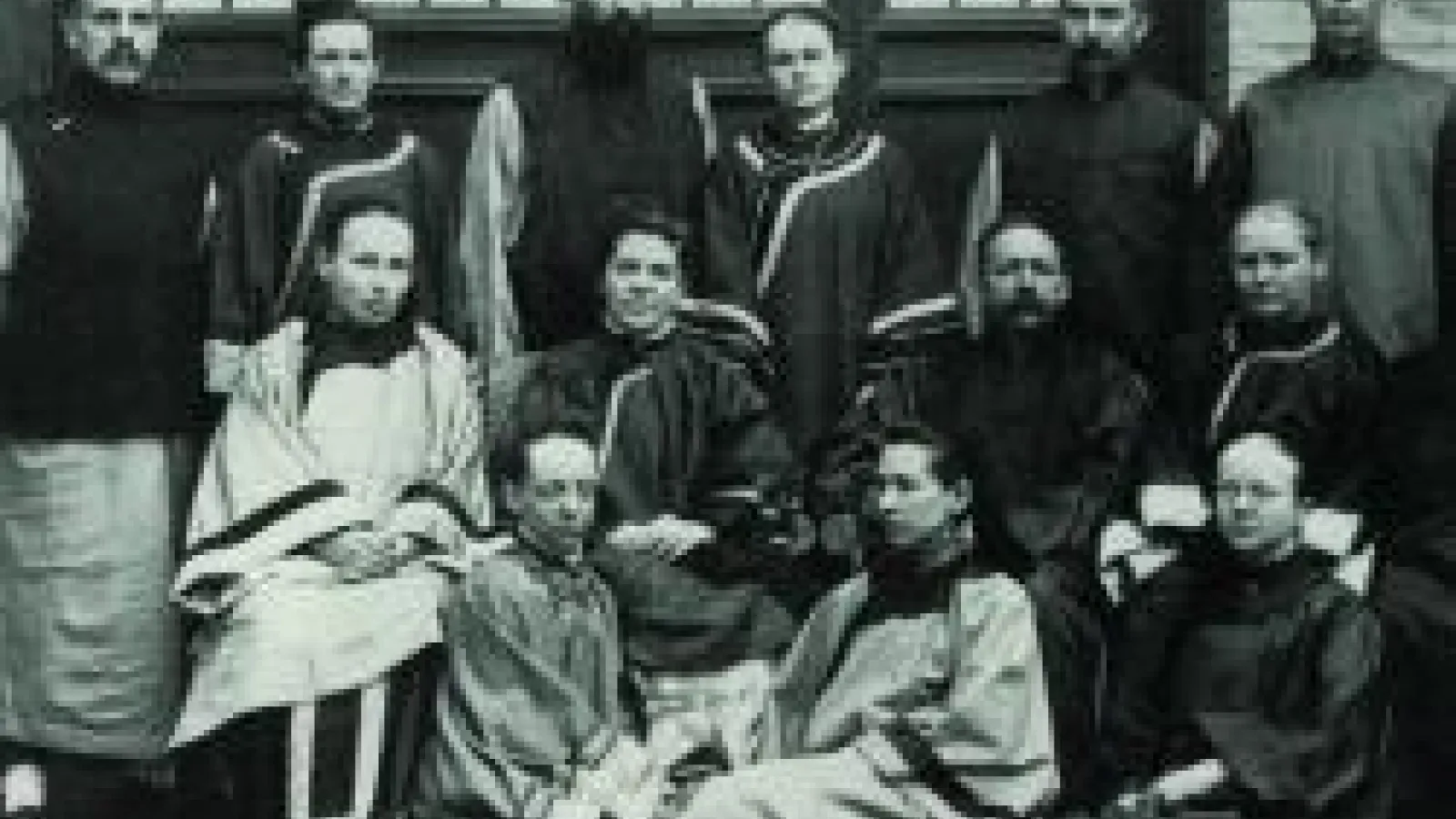 A group of men in clerical robes, some sitting in chairs and some sitting on floor. 