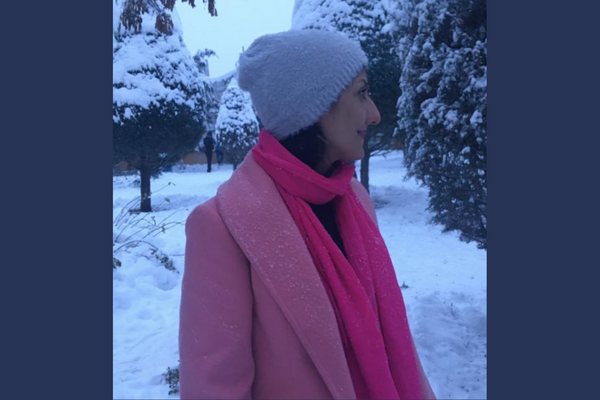 Zahra is standing in the snow with a pink coat and bright pink scarf and lavender hat